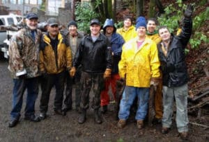 Harbor men chop wood in the rain to provide fire wood for families in need.