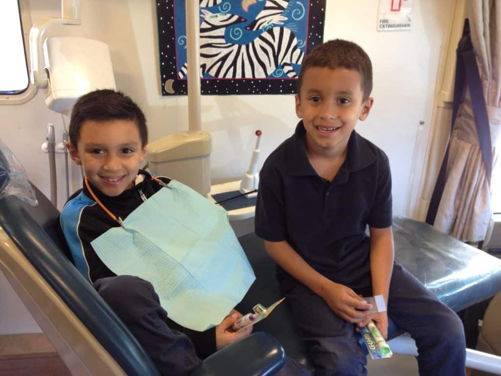 A couple of boys from Shepherd's Door finish up their appointment with Medical Teams International's Mobile Dentist Program.