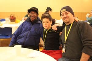 "T-Bone" (left) sits with two of our most faithful volunteers at our 2015 Thanksgiving Dinner at the Burnside Shelter.