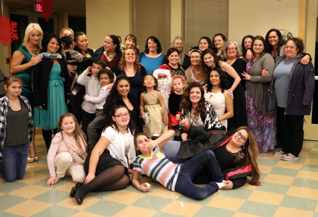 A group of ladies from Shepherd's Door and their children take a moment away from some Christmas festivities to take a fun photo together.